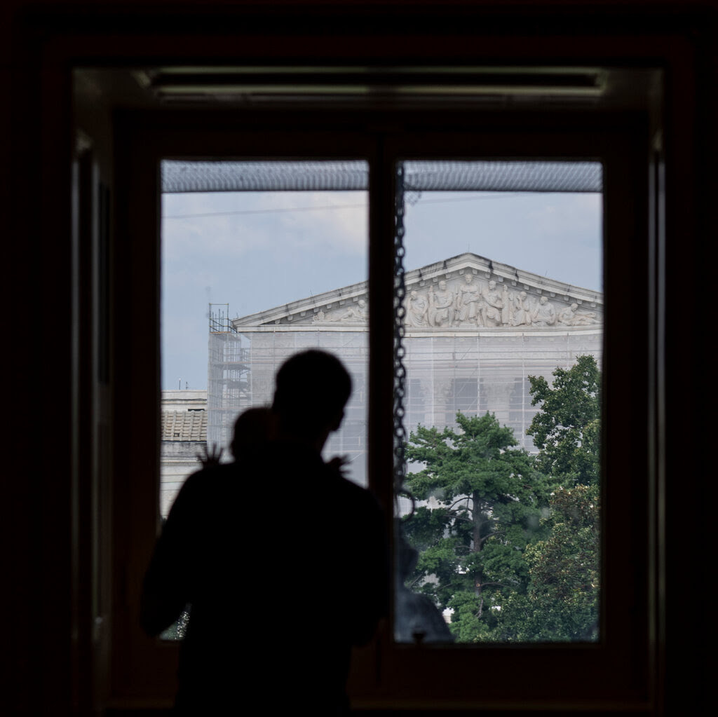 A father and his child look over at the U.S. Supreme Court from Capitol Hill.
