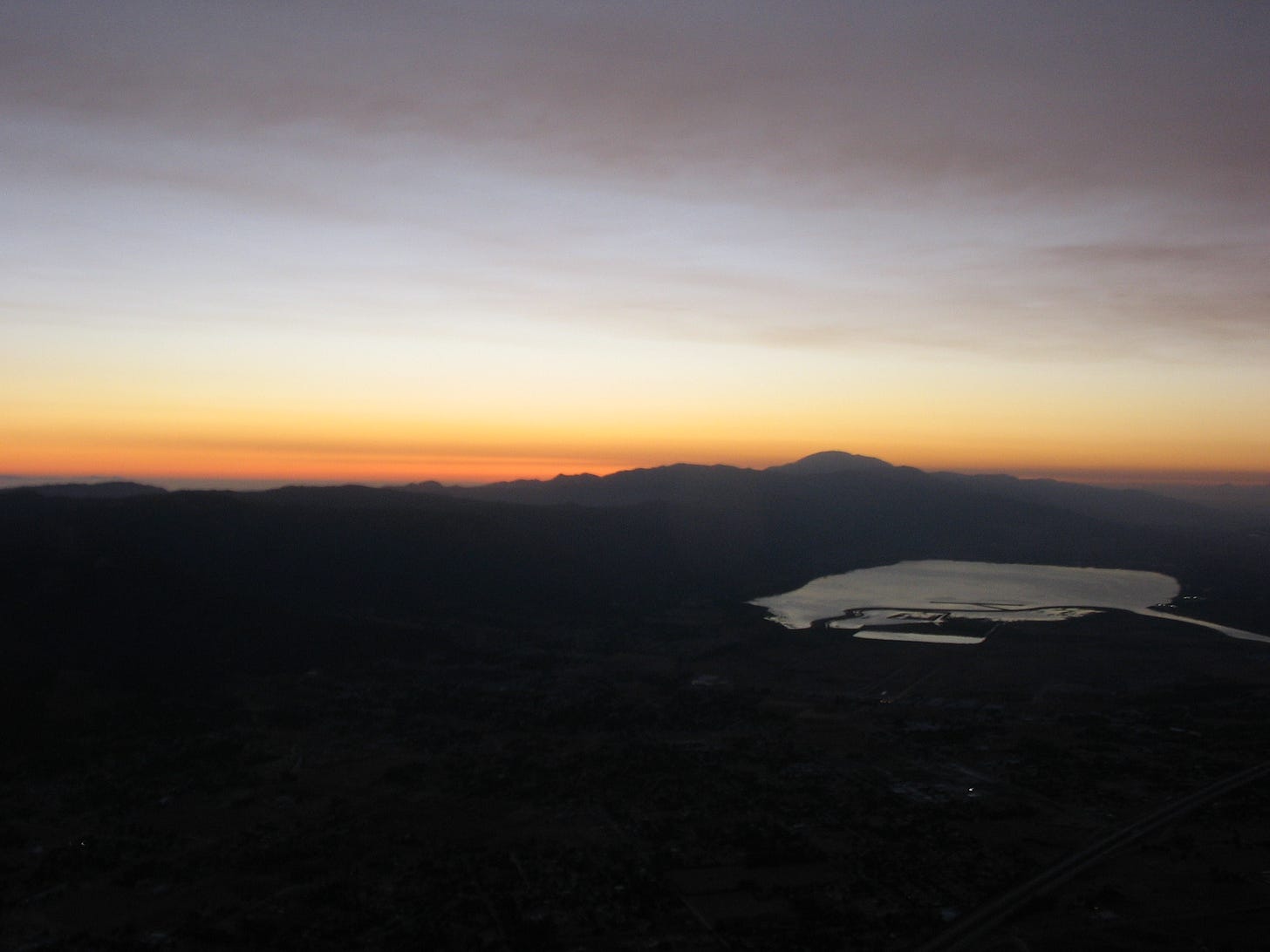Aerial view of Lake Elsinore at sunset, with orange sky above and dark mountains and the lake below. Aerial view of Lake Elsinore at sunset, with orange sky above and dark mountains and the lake below.