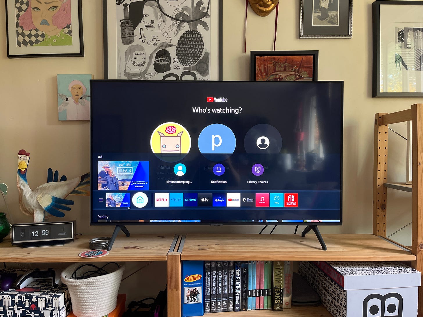 Photo of a TV with the main menu open at the bottom of the screen. It shows a row of icons along the bottom of the screen, but they are raised slightly from the bottom edge by a sliver of another interface. The tops of five video thumbnails poke in from the bottom along with the heading "Reality"
