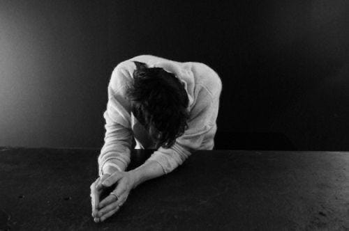 This may contain: black and white photograph of a person leaning on a table with their hands in the ground