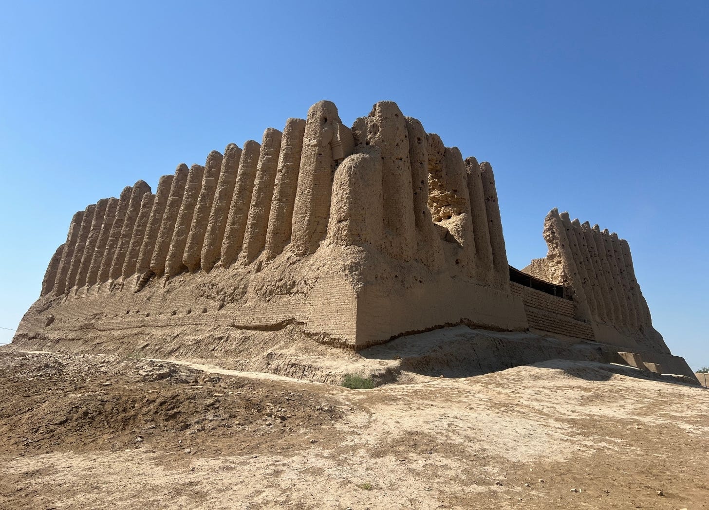 Sand-colored ancient ruins of a citadel wall against a bright blue sky. Sand-colored ancient ruins of a citadel wall against a bright blue sky.