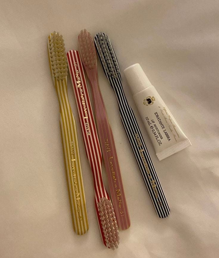 This may contain: three different colored toothbrushes sitting next to each other on a white bed sheet