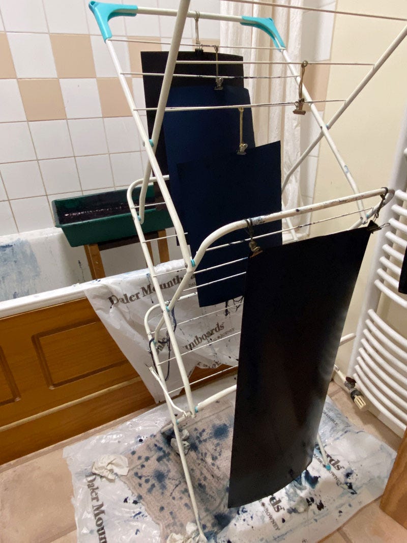 Freshly dyed indigo paper hanging from a rack to drip in a very cramped space
