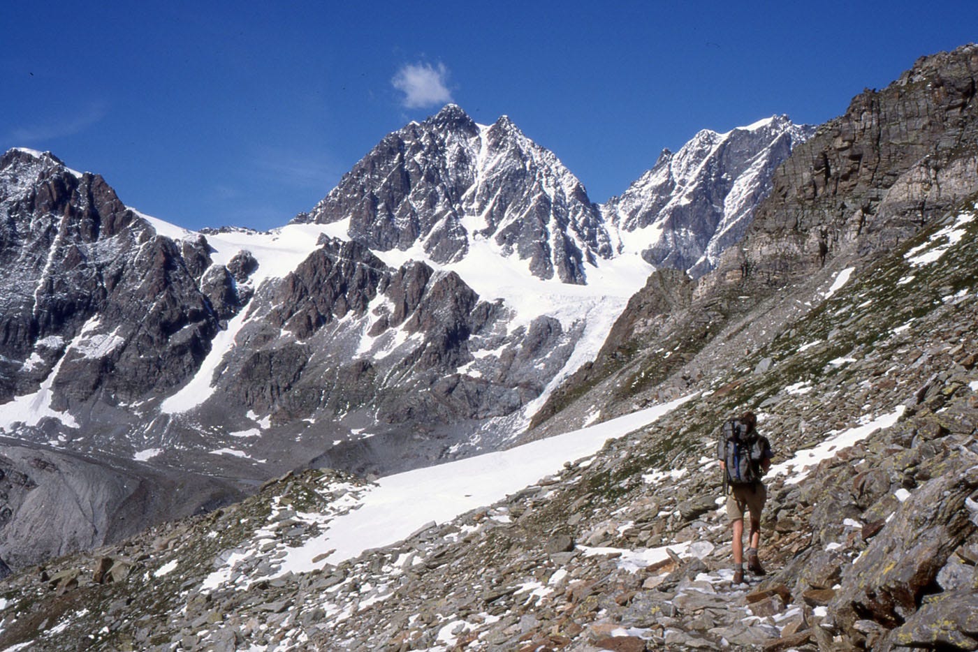 Stony mountainside, rock and snow peaks above
