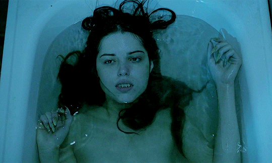 This may contain: a woman in a bathtub with her hair blowing back