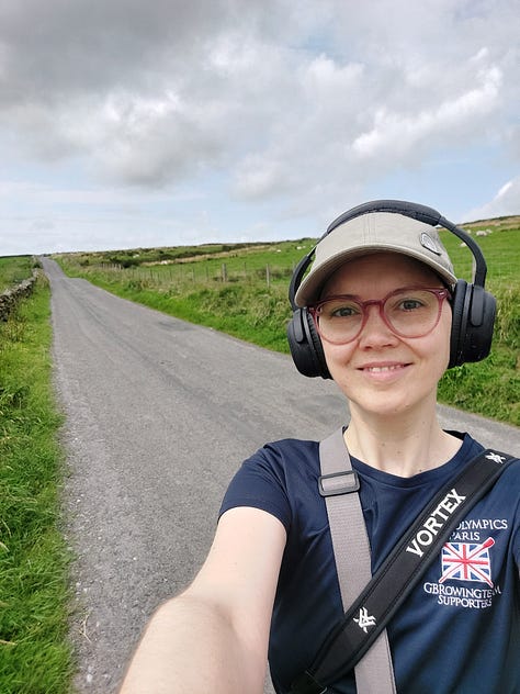 Smiling selfies of me mid walk. Behind me you see pink blooming Himalayan Balsam. In another picture is a straight grey road disappearing into the horizon. In another is a body of water, some grey clouds and lush grass in the foreground. Other pictures are of nature, a close up of an orange and black painted lady butterfly, dappled sun shining through woodland pines and a canal with reeds along its edge and algae on the water