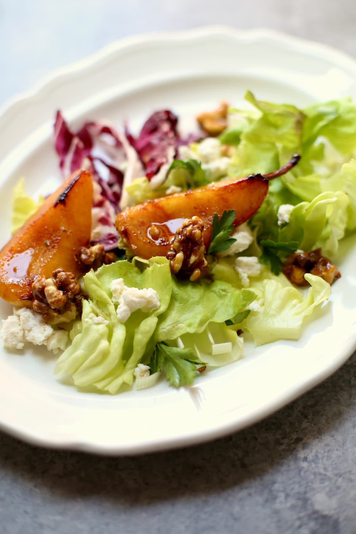 a roasted pear salad on greens and on a white platter