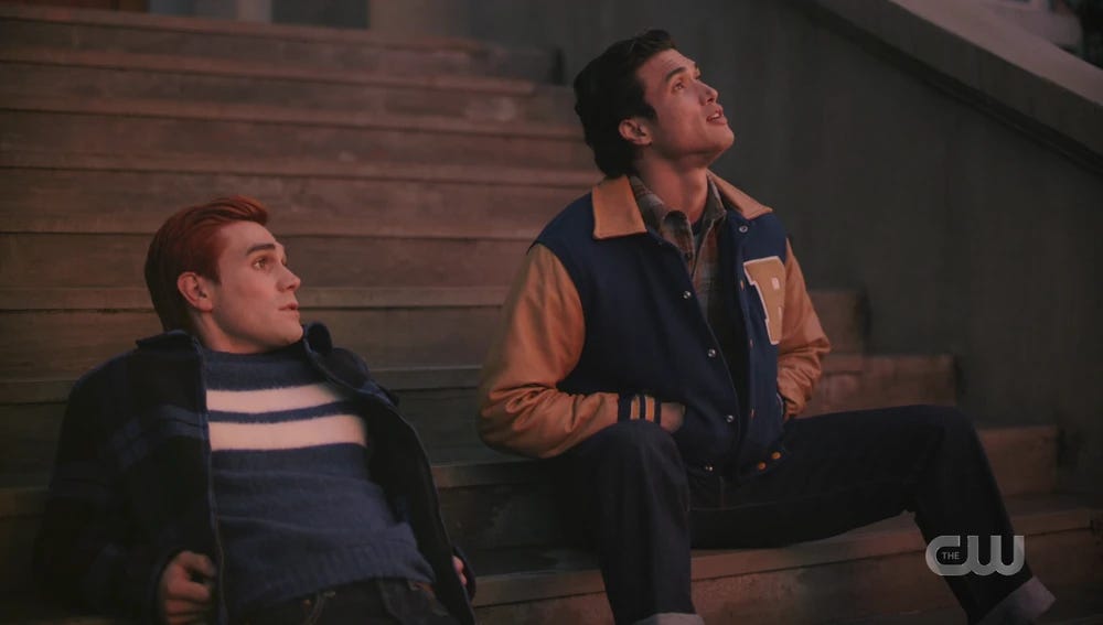 Archie and Reggie sitting on the school steps and looking up at the sky.