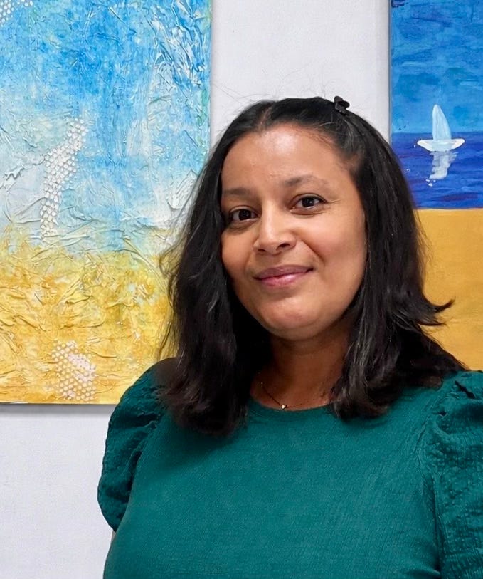 Young woman looking into the camera, yellow and blue painting behind her