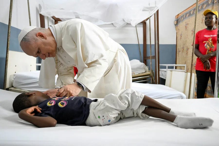 Pope Leo XIV leans over a child in a hospital bed at St. Paul Catholic Hospital in Douala, Cameroon Pope Leo XIV leans over a child in a hospital bed at St. Paul Catholic Hospital in Douala, Cameroon