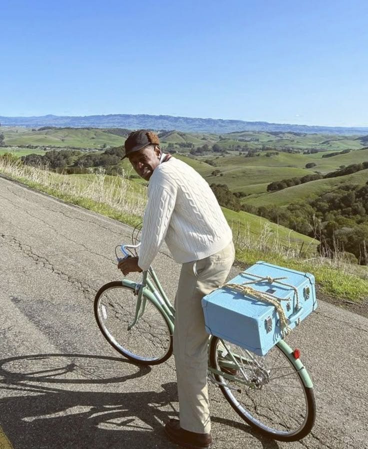 This may contain: a man riding a bike down a road next to a blue box on the back of it