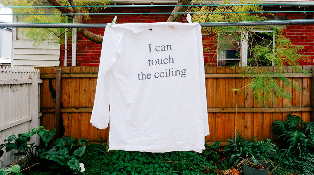 a long sleeve white t-shirt with I can touch the ceiling printed on it.