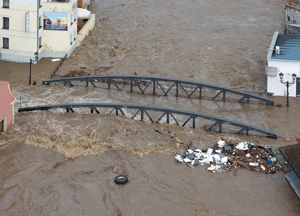 A bridge and surrounding buildings submerged in brown floodwaters
