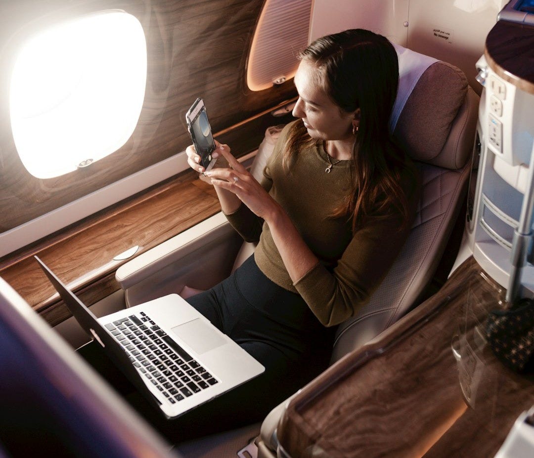 a woman sitting in an airplane looking at her cell phone a woman sitting in an airplane looking at her cell phone