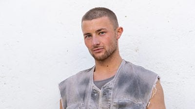 Jordan B wears a sleeveless, distressed denim jacket over a vest