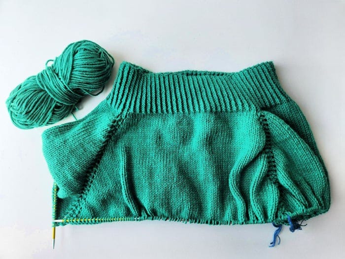 Sleeve stitches held on scrap yarn and body stitches on the circular needle