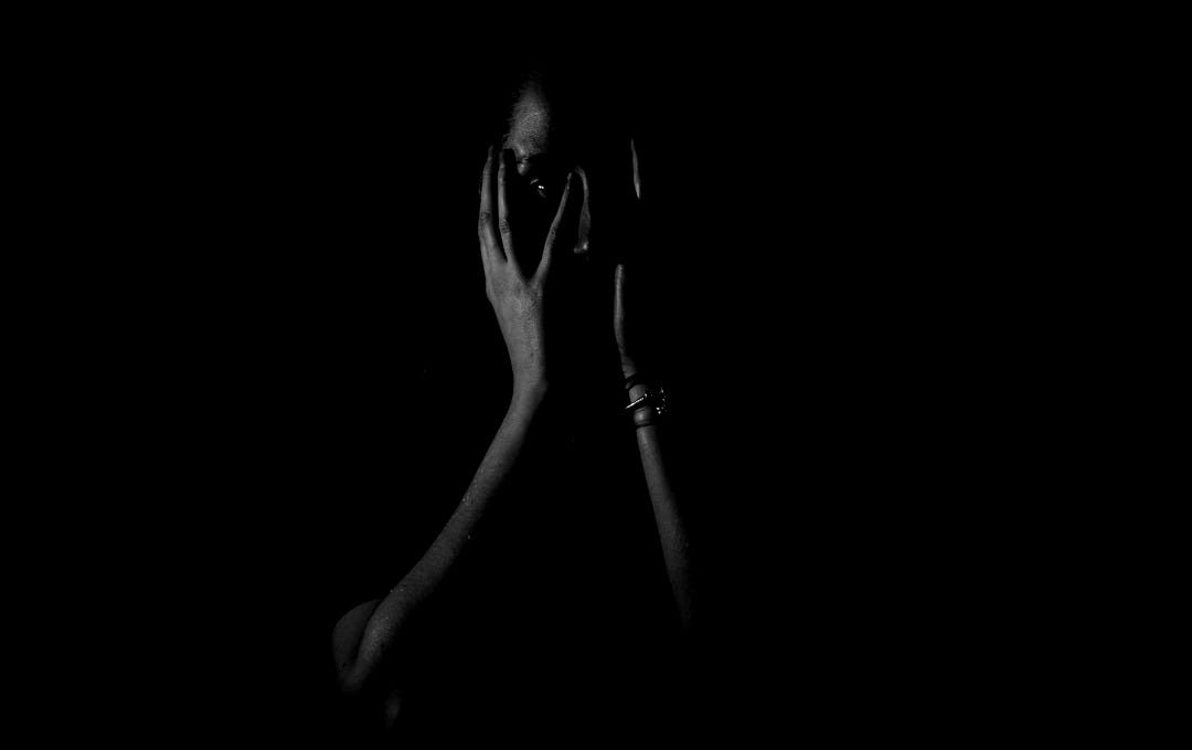 woman holding her face in dark room woman holding her face in dark room