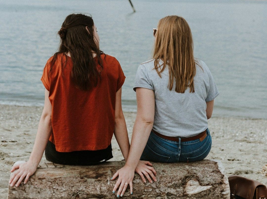 two women sitting on log two women sitting on log