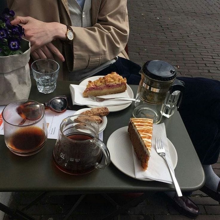 This may contain: a person sitting at a table with some food and drinks on it, in front of them