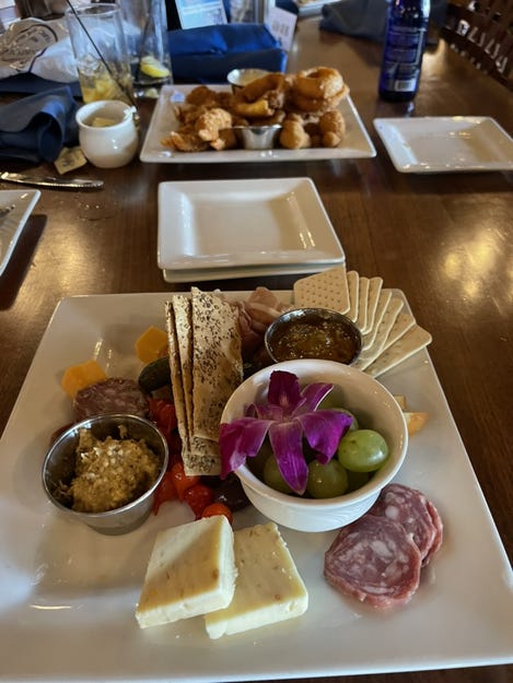 A beautifully arranged charcuterie board garnished with a purple orchid.