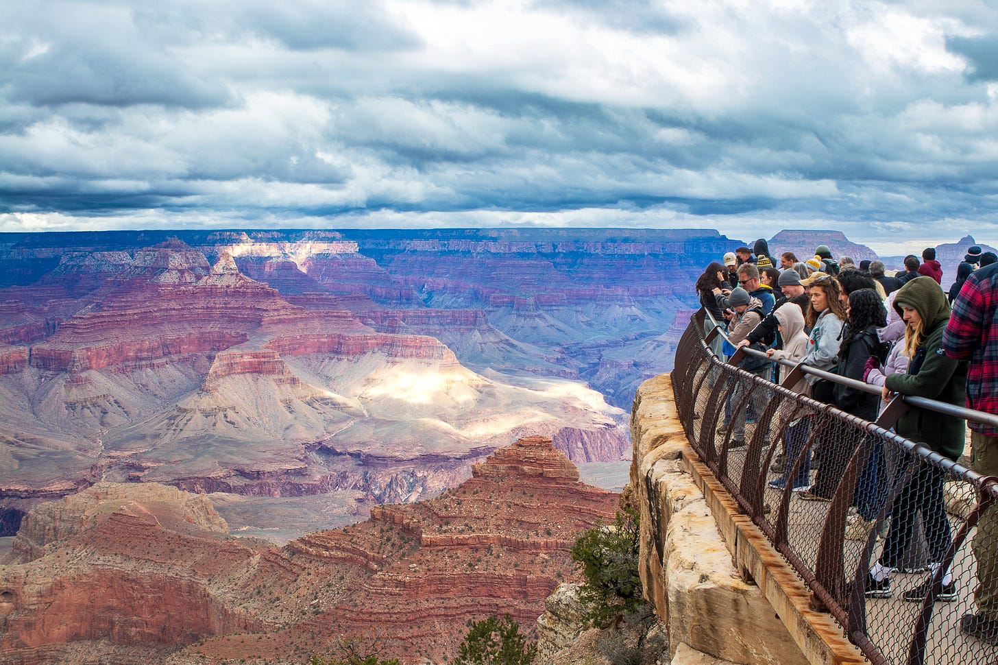 Crowd of tourists along a rail overlooking the Grand Canyon Crowd of tourists along a rail overlooking the Grand Canyon