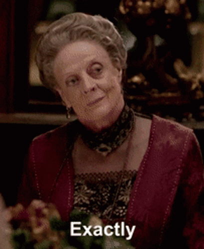 a woman in a red dress says exactly in front of a vase of flowers .
