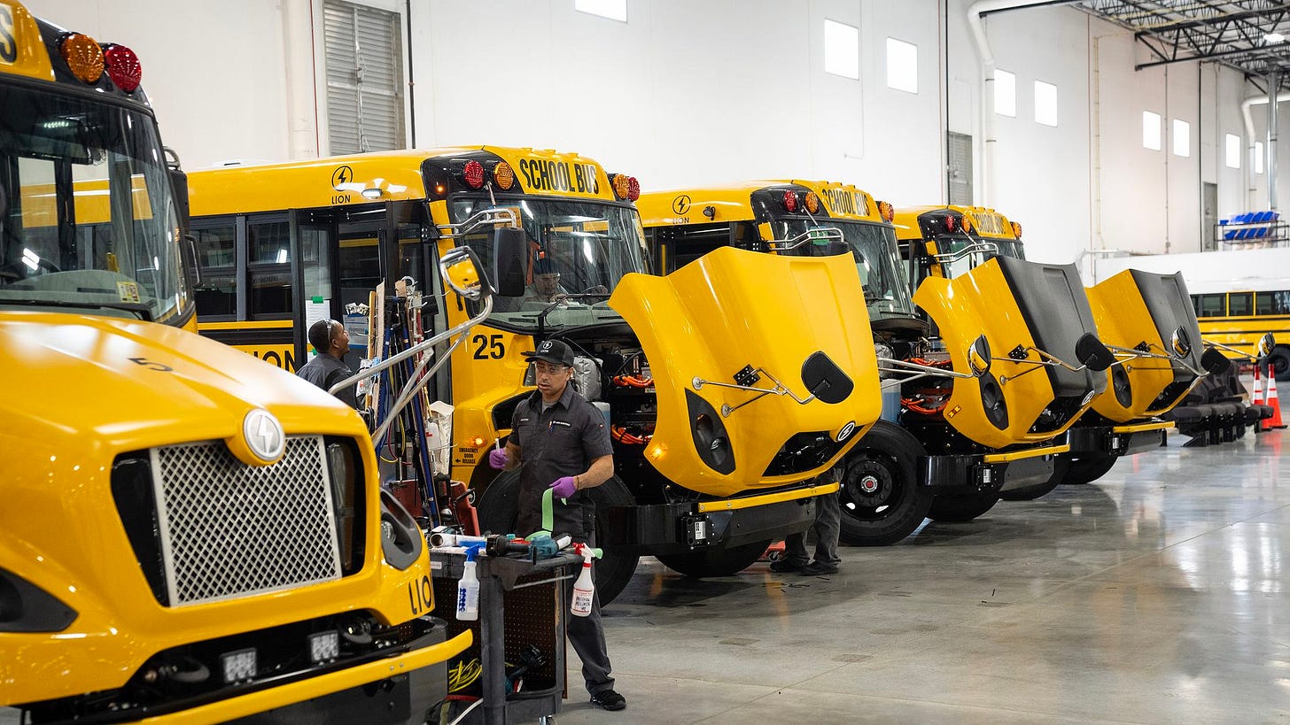 Workers inspect and repair electric yellow school buses with open hoods inside Lion Electric's Illinois factory, which has since closed. Workers inspect and repair electric yellow school buses with open hoods inside Lion Electric's Illinois factory, which has since closed.
