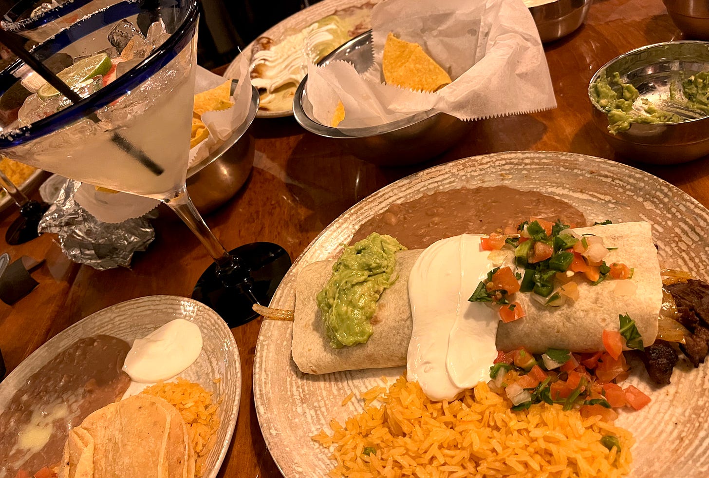 table full of burritos, drinks, rice, beans and chips