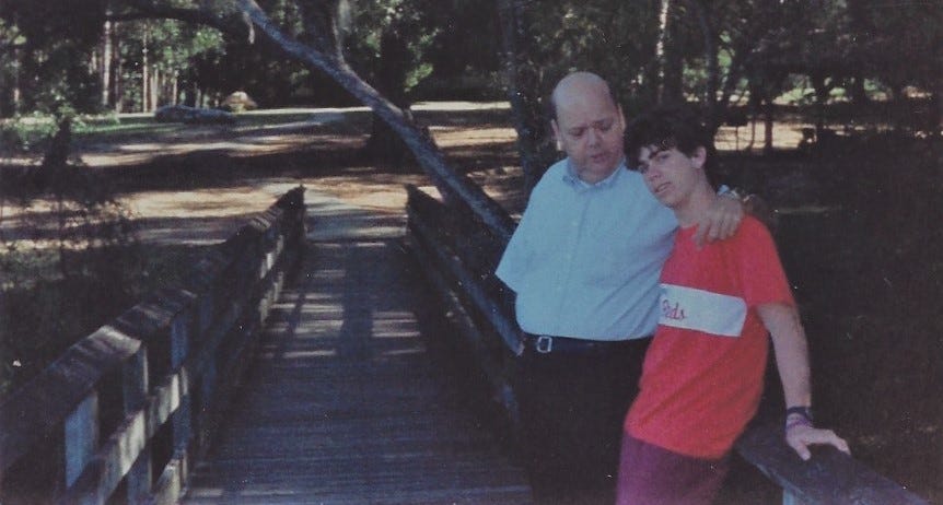 Dad with his arm around my shoulder talking to me on a bridge in a Florida park.