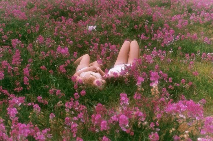 This may contain: a woman laying in the middle of a field of flowers