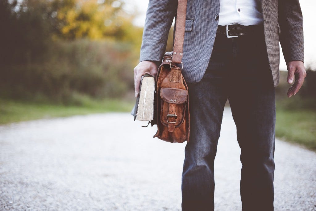 Working professional holding a book and bag, on the way to work.