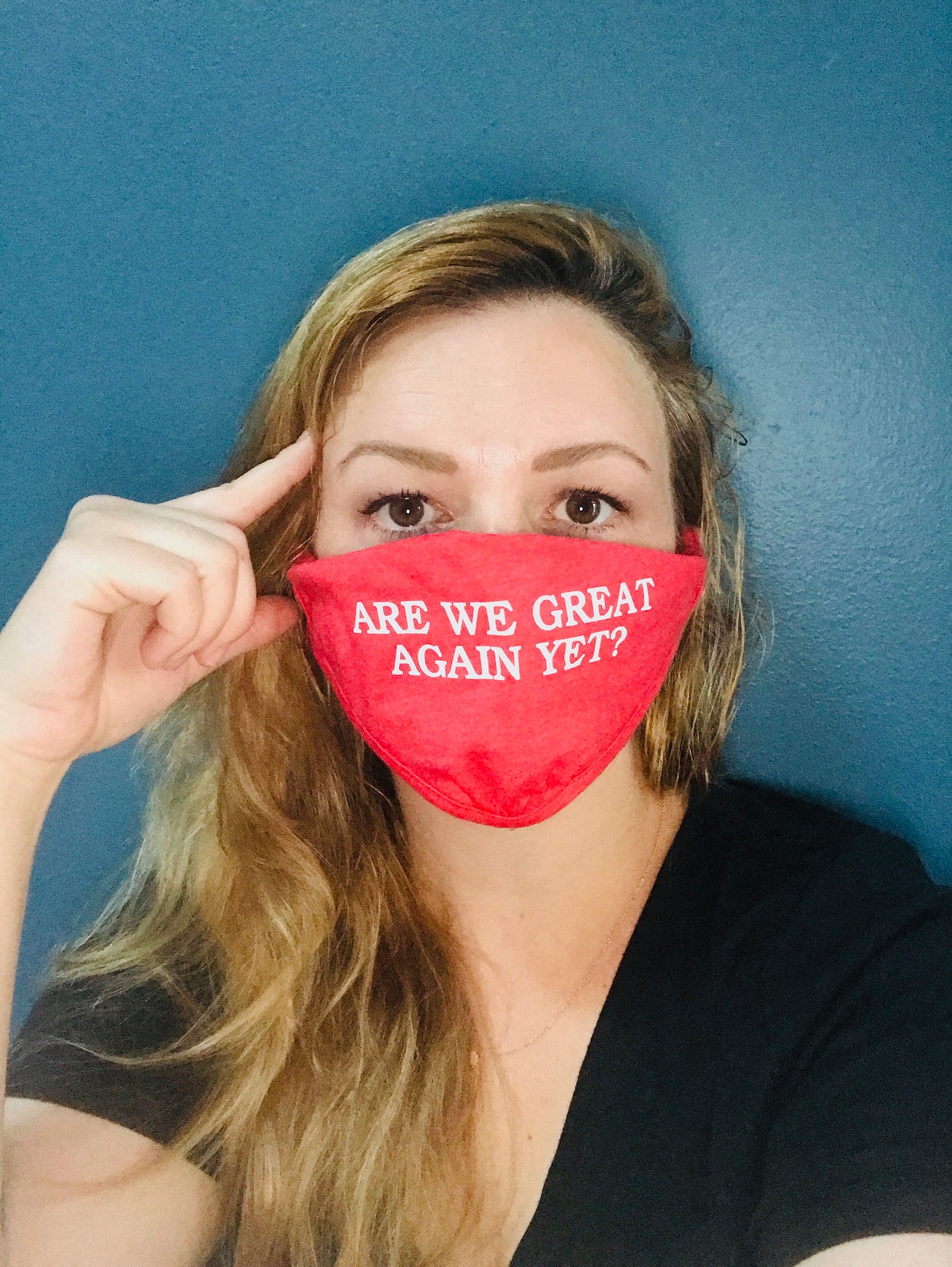 A photo from the shoulders up of Amber wearing a red face mask. She looks directly into the camera. Written on her mask in all capital letters is "Are we great again yet?"