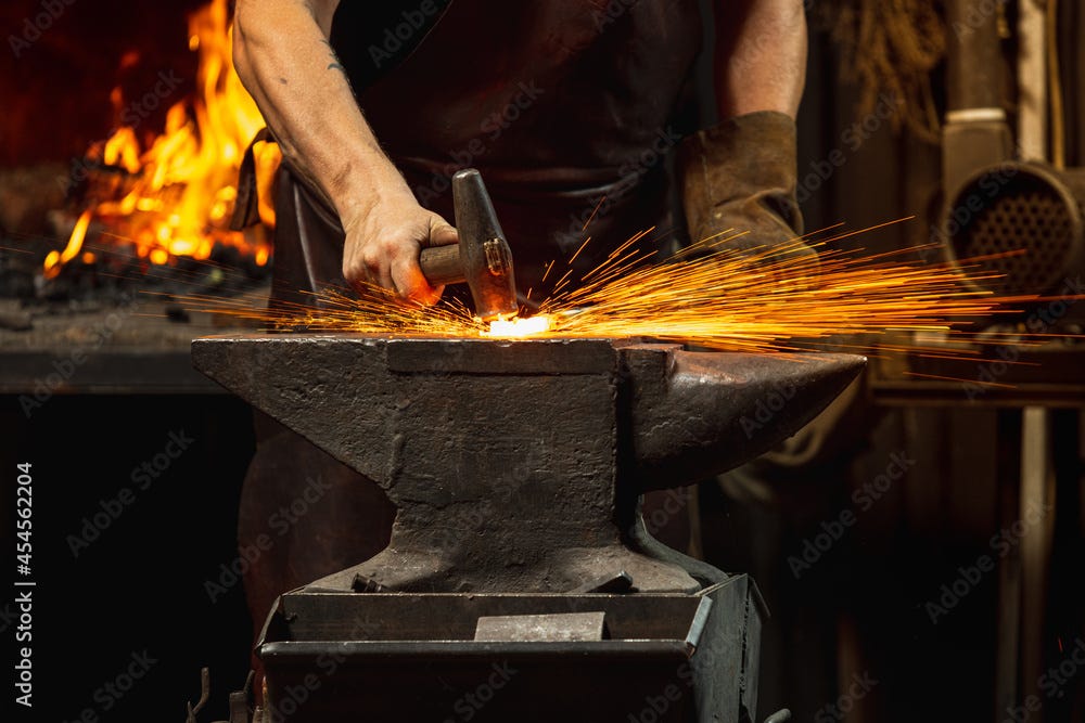 Close-up working powerful hands of male blacksmith forge an iron product in a blacksmith. Hammer ...