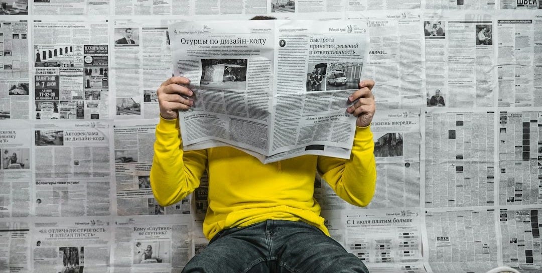 a person sitting on the floor reading a newspaper a person sitting on the floor reading a newspaper