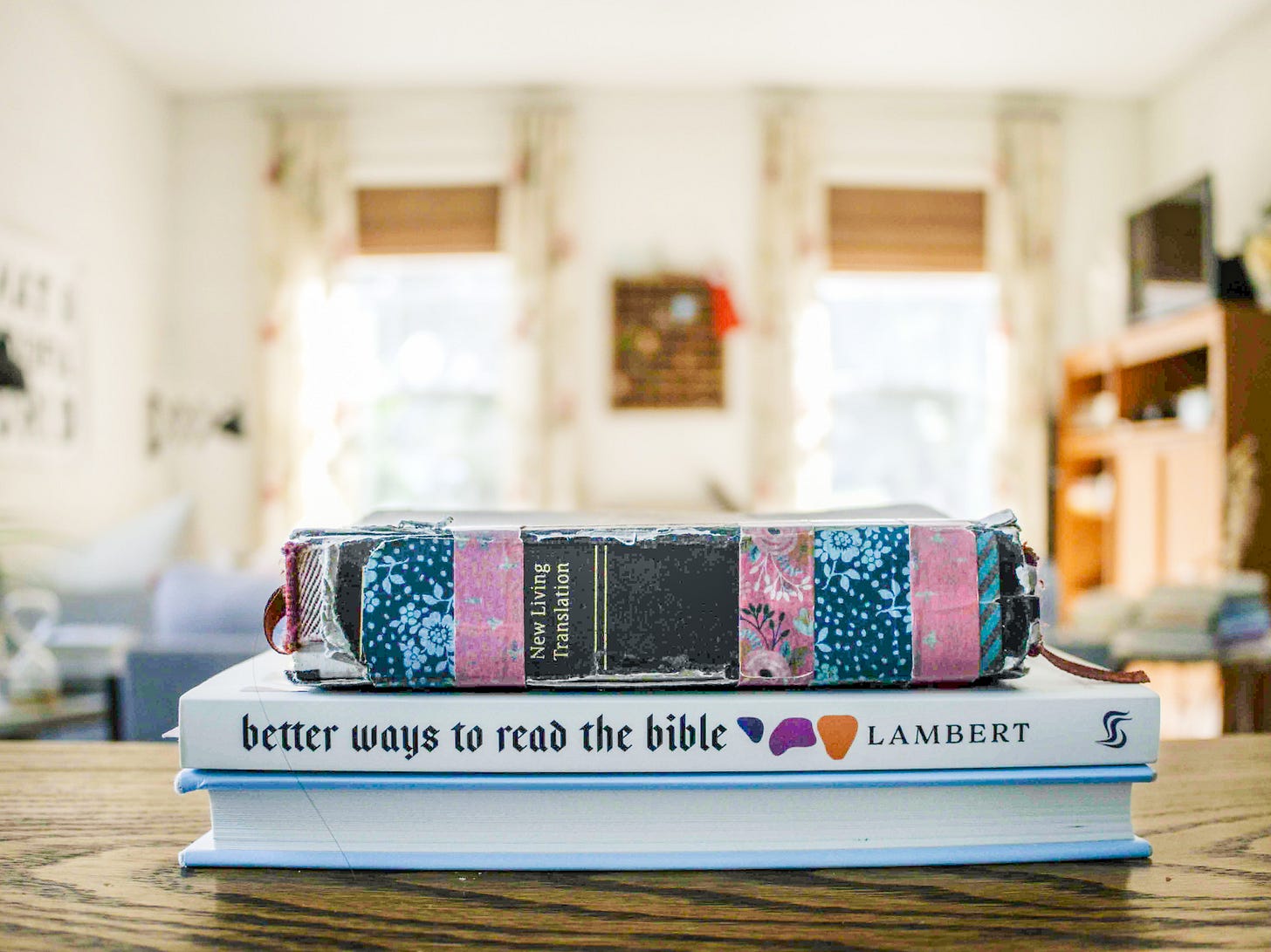 A stack of books on a table, a blue book (untitled), then Better Ways to Read the Bible by Zach Lambert, then a well-worn Bible