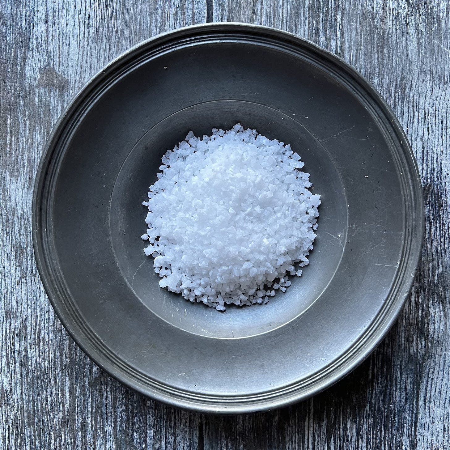 coarse rock salt in centre of shallow pewter plate coarse rock salt in centre of shallow pewter plate