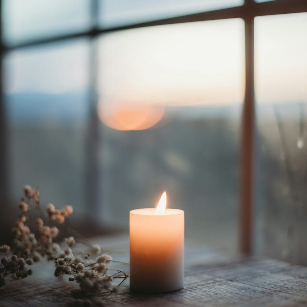 a lit candle sitting on top of a wooden table