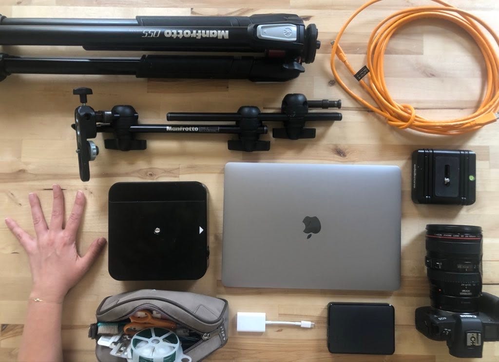 A grid of photo equipment that includes a laptop, camera rigs, and a left hand.