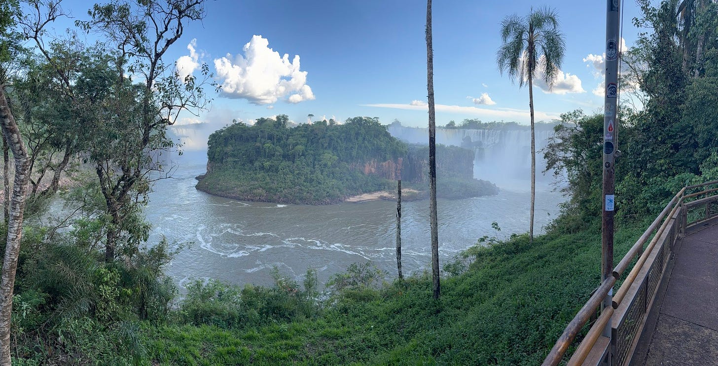A view of the waterfalls in the distance from the lower falls walking path. Between the waterfalls and path is a small island.