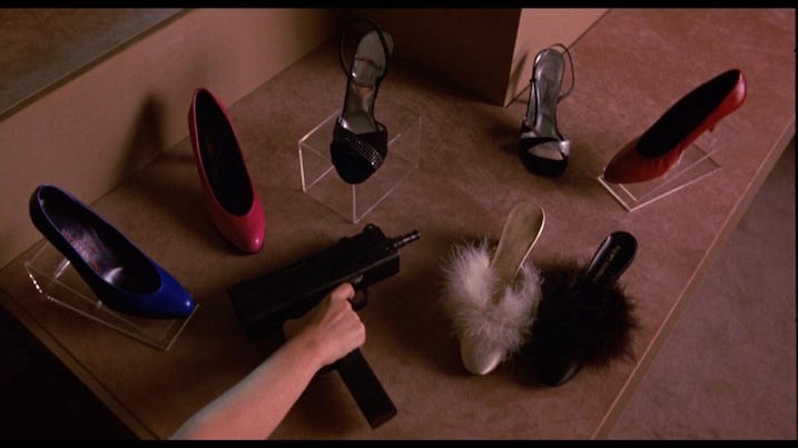 Night of the Comet (1984) still showing a woman’s hand reaching for an Uzi surrounded by high heels in a mall store display.
