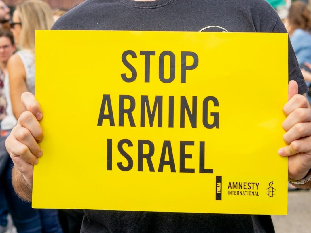 Man holds yellow sign saying stop arming israel