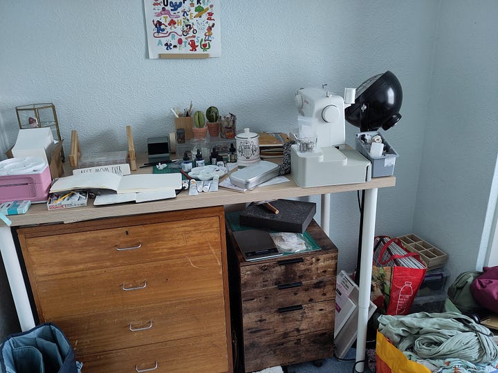 two pictures of a small studio room. The left picture shows a desk with a sewing machine and art materials. The right picture shows a green chair in the corner near a window next to boxes, a bookshelf, and art supplies.