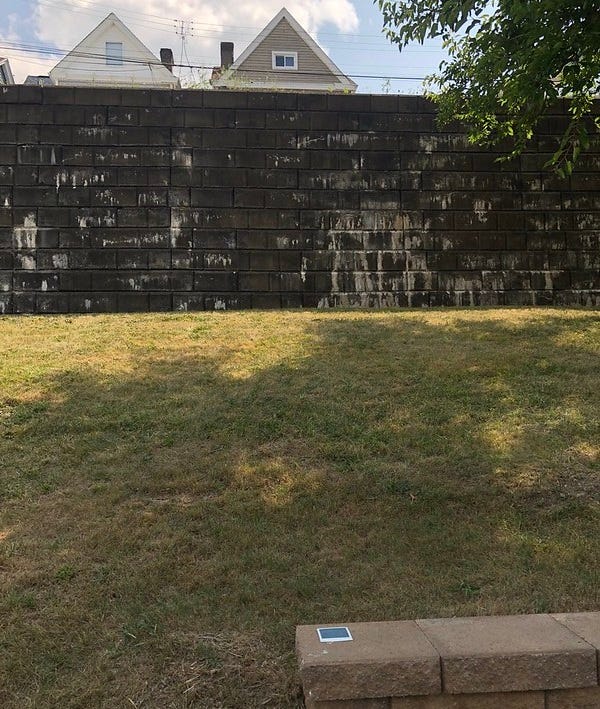 Old retaining wall with rooftops peeping over the top.