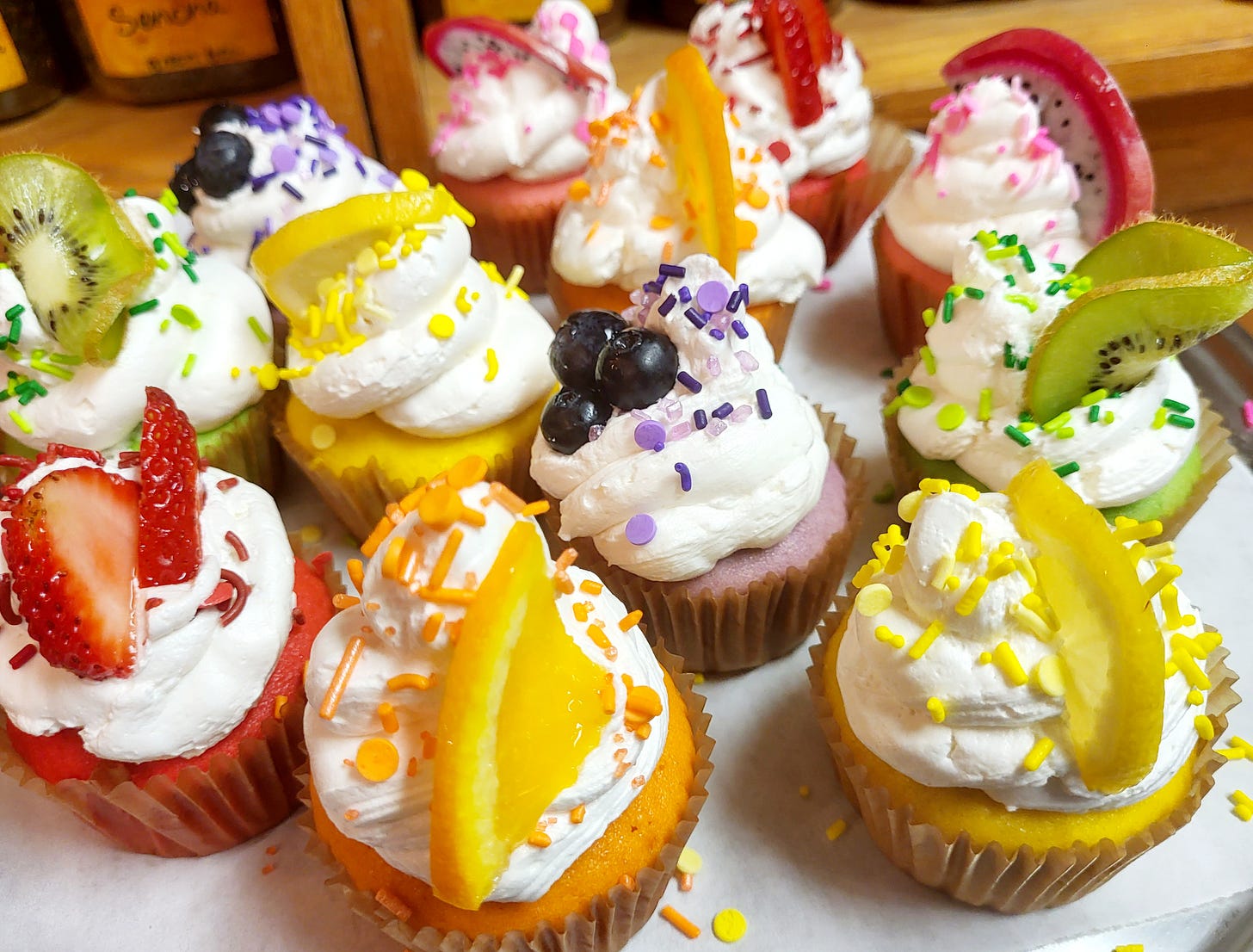 An assortment of cupcakes featuring fruit toppings, elegantly arranged on a serving tray.