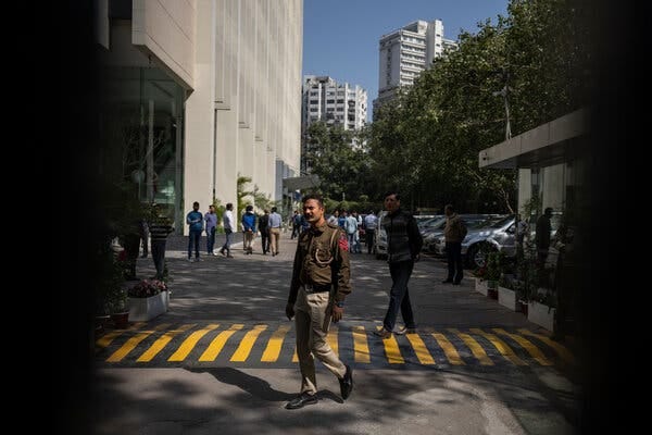 A man in uniform roams around a parking lot in front of an office building. A man in uniform roams around a parking lot in front of an office building.