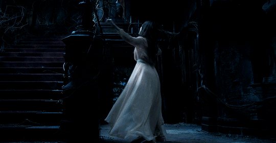 This may contain: a woman in a white dress is walking up some stairs at night with her hand on the railing