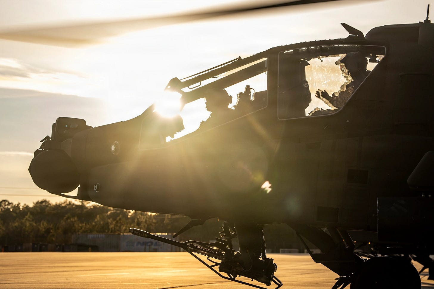 Silhouette of an AH-64 Apache pilot in the cockpit during pre-flight checks at sunset