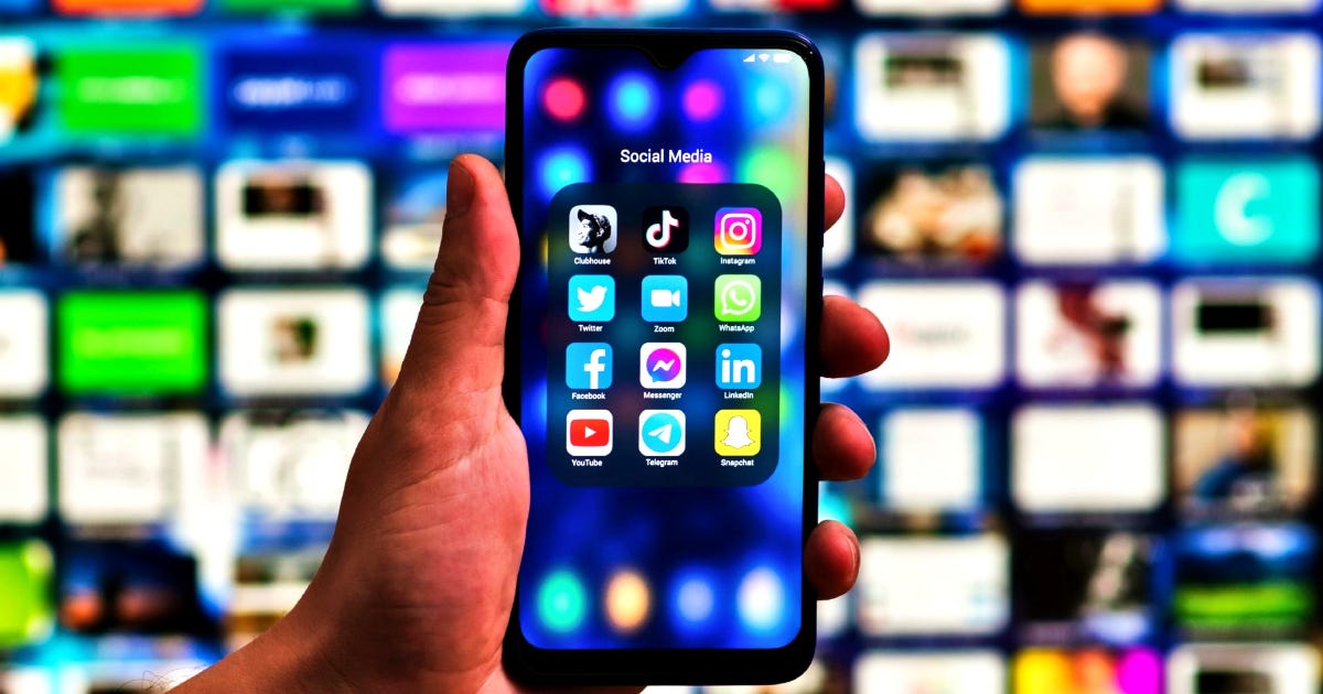 Social media apps on a smartphone in focus in front; streaming service apps on a blurry TV screen in the back Social media apps on a smartphone in focus in front; streaming service apps on a blurry TV screen in the back