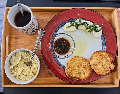 hands holding five pints of ice cream, a hand holding a perfume sample in front of a big green plant leaf, four lip products on a table in front of a sand zen garden and vase, a handful of shaved curly black hair, a hand holding a light beige mug with illustrated plants all over it, an above view of a meal on a plate with toasted english muffins, black tea, mozarella slices, and ramen