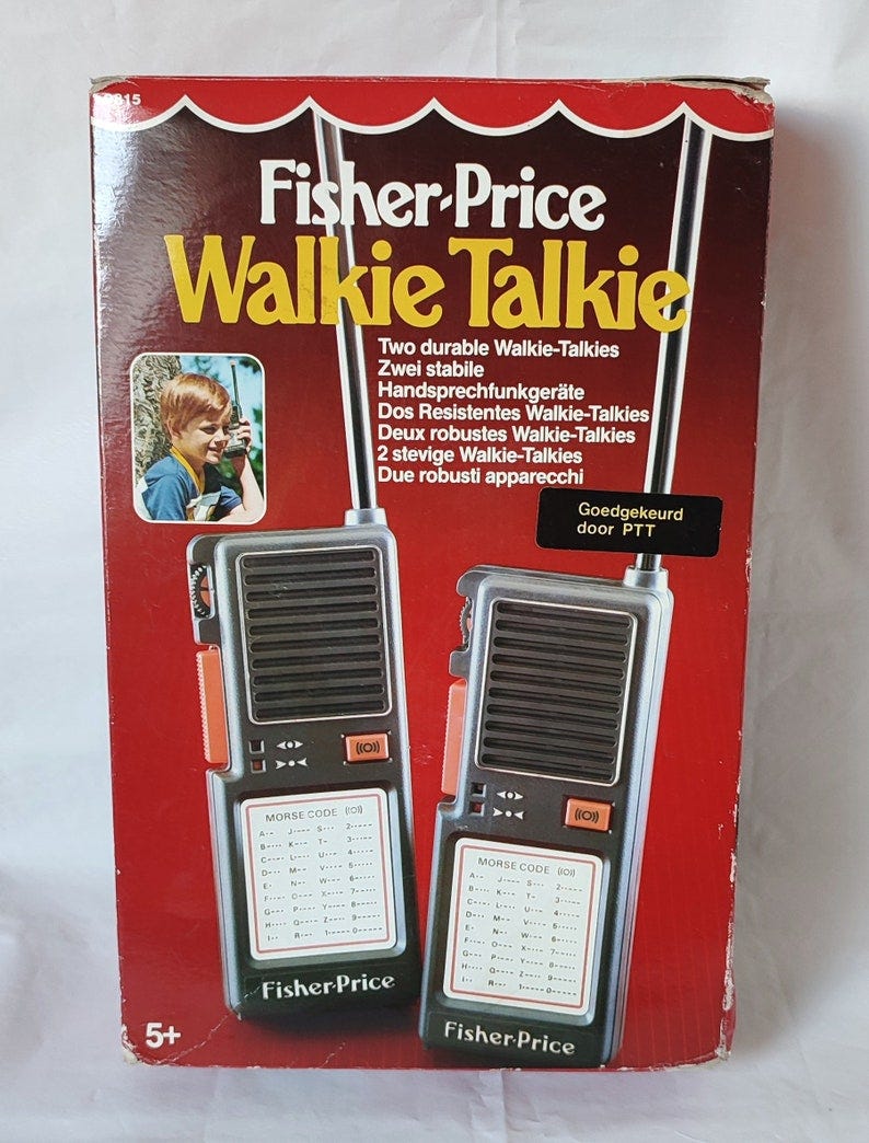 May include: Fisher-Price Walkie Talkie box with two black walkie talkies. The box is red and has a picture of a boy using a walkie talkie. The box says 'Two durable Walkie-Talkies' and 'Goedgekeurd door PTT'. May include: Fisher-Price Walkie Talkie box with two black walkie talkies. The box is red and has a picture of a boy using a walkie talkie. The box says 'Two durable Walkie-Talkies' and 'Goedgekeurd door PTT'.